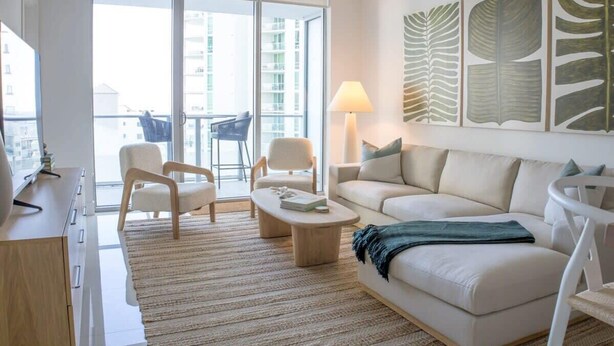 Un salon moderne avec un canapé, des fauteuils, une table basse et une lampe.