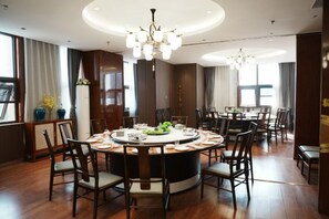 A spacious dining area with a round table, multiple chairs, and a chandelier. - ZHONGZHOU INTERNATIONAL HOTEL (Xinyang)