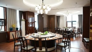 A dining area with a round table, chairs, a chandelier, and a view of the outdoors.