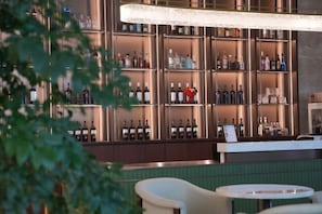 A bar area with shelves of bottles, a counter, and two round tables. - ZHONGZHOU INTERNATIONAL HOTEL (Xinyang)