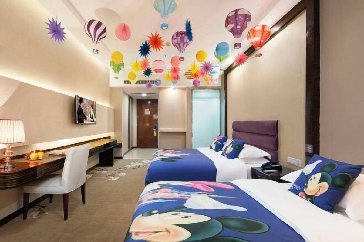 Ein Hotelzimmer mit zwei Betten, einem Schreibtisch, einem Stuhl und einem Fernseher.
