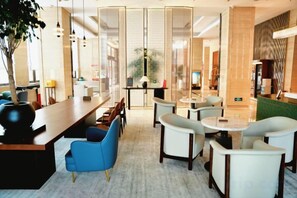 A modern hotel lobby with a long reception desk, seating area, and a glass partition. - ZHONGZHOU INTERNATIONAL HOTEL (Xinyang)