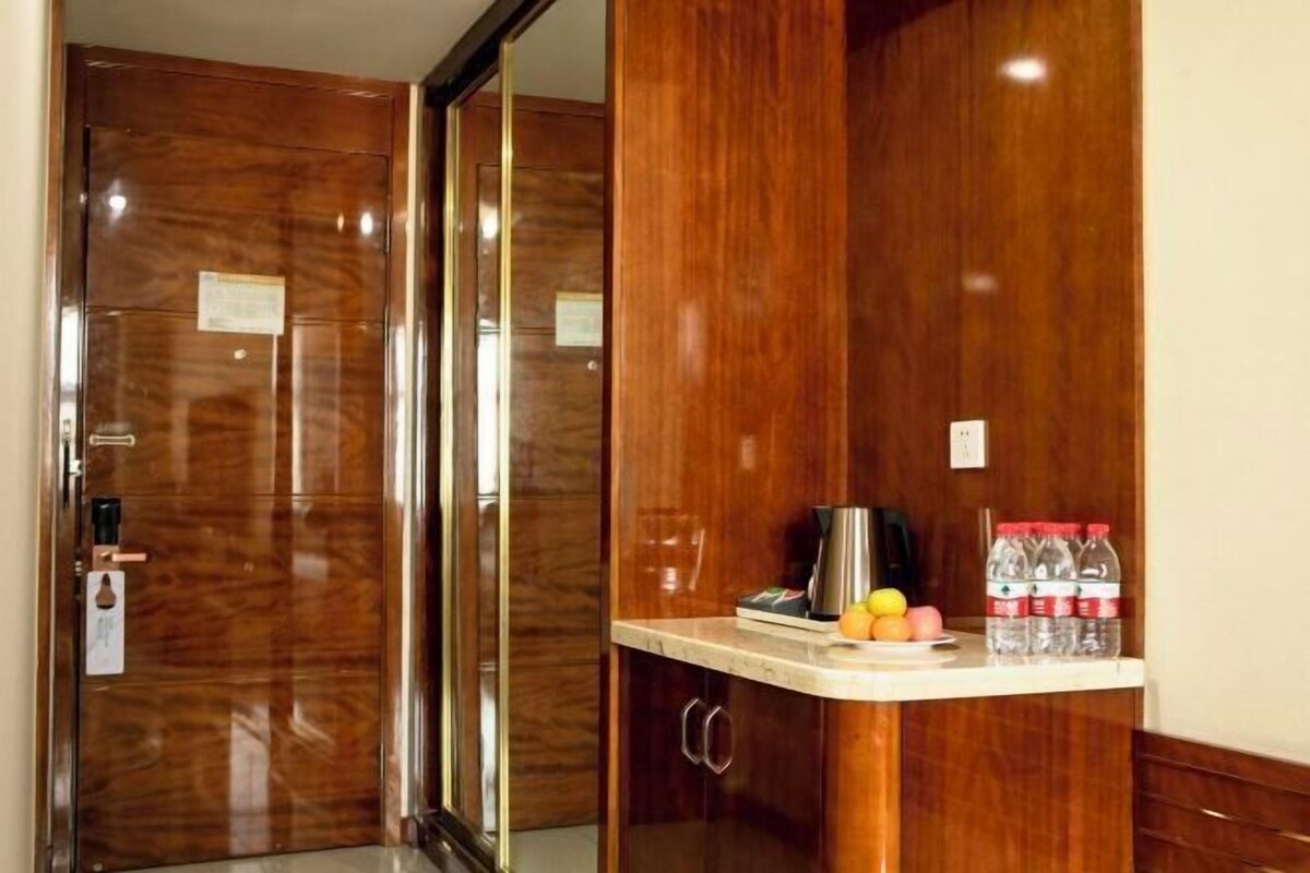 A wooden wardrobe with a mirror, a small countertop with a kettle, a coffee maker, and bottled water.