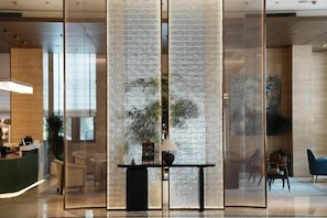 A modern hotel lobby with a reception desk, seating area, and a decorative wall. - ZHONGZHOU INTERNATIONAL HOTEL (Xinyang)