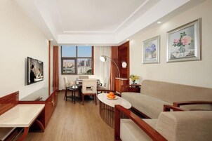 A modern hotel room with a dining area, a sofa, and artwork on the walls.