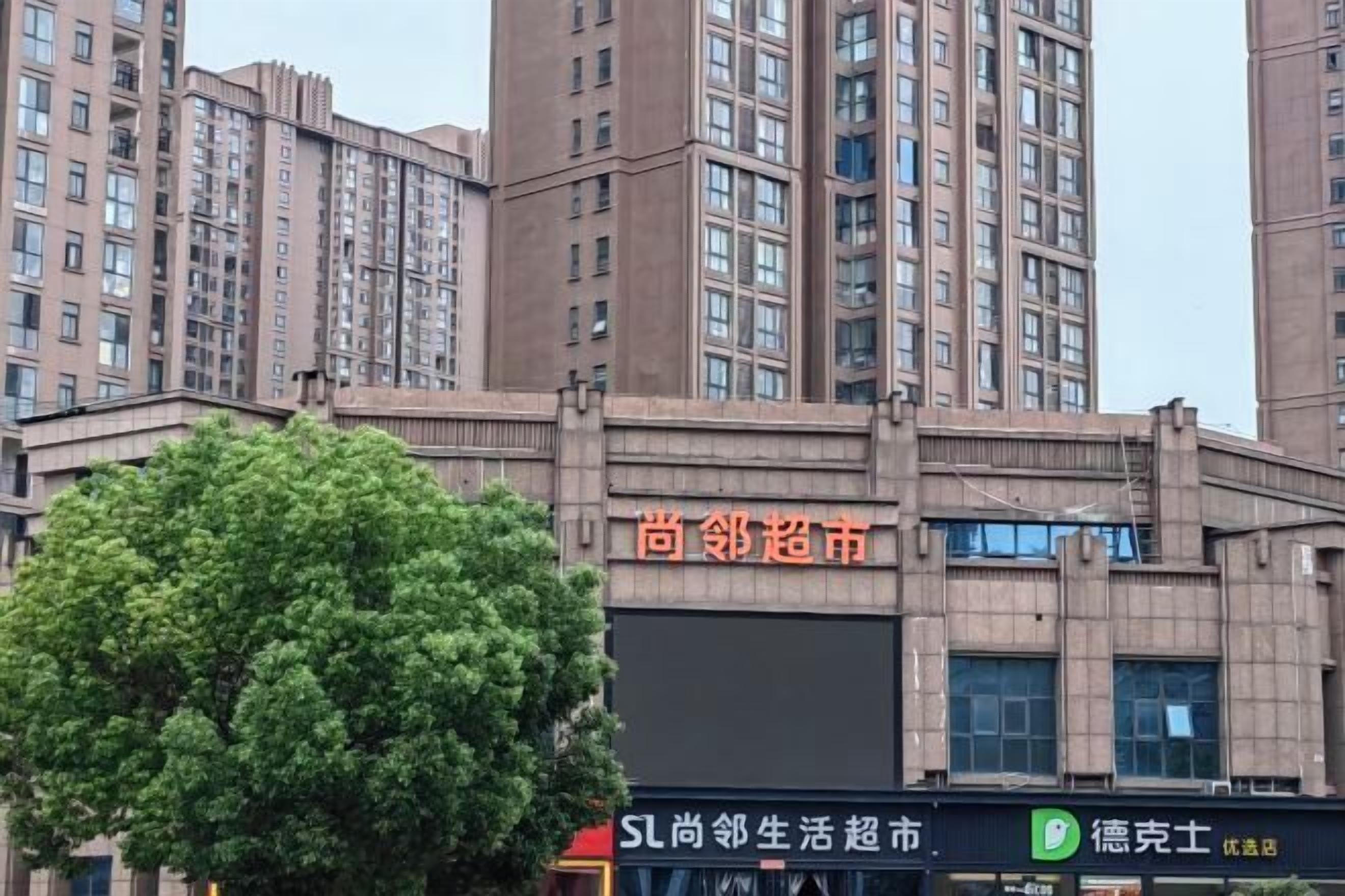 Un edificio de varios pisos con un cartel que dice '尚邻超市' (Shang Nei Supermarket).