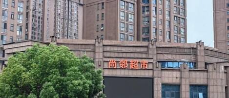 Un edificio de varios pisos con un cartel que dice '尚邻超市' (Shang Nei Supermarket).