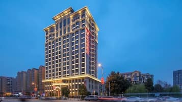 A multi-story hotel with a classic architectural design, featuring a prominent entrance and illuminated signage.