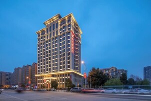 A multi-story hotel with a classic architectural design, featuring a prominent entrance and illuminated signage.