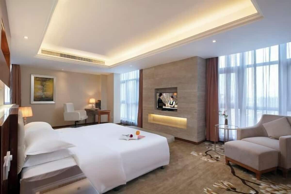 Ein Hotelzimmer mit Bett, Fernseher, Sitzecke und großem Fenster.