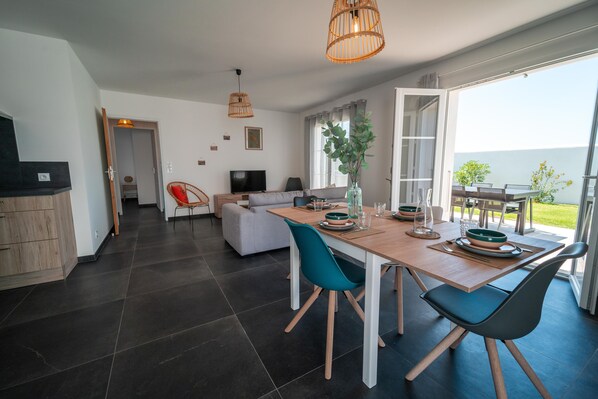 Enjoy a spacious living area with a large window offering a view of the outdoors, a comfortable sofa, and a dining table with chairs.