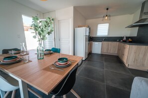 Enjoy meals in this stylish kitchen and dining area, featuring a wooden table and modern appliances.