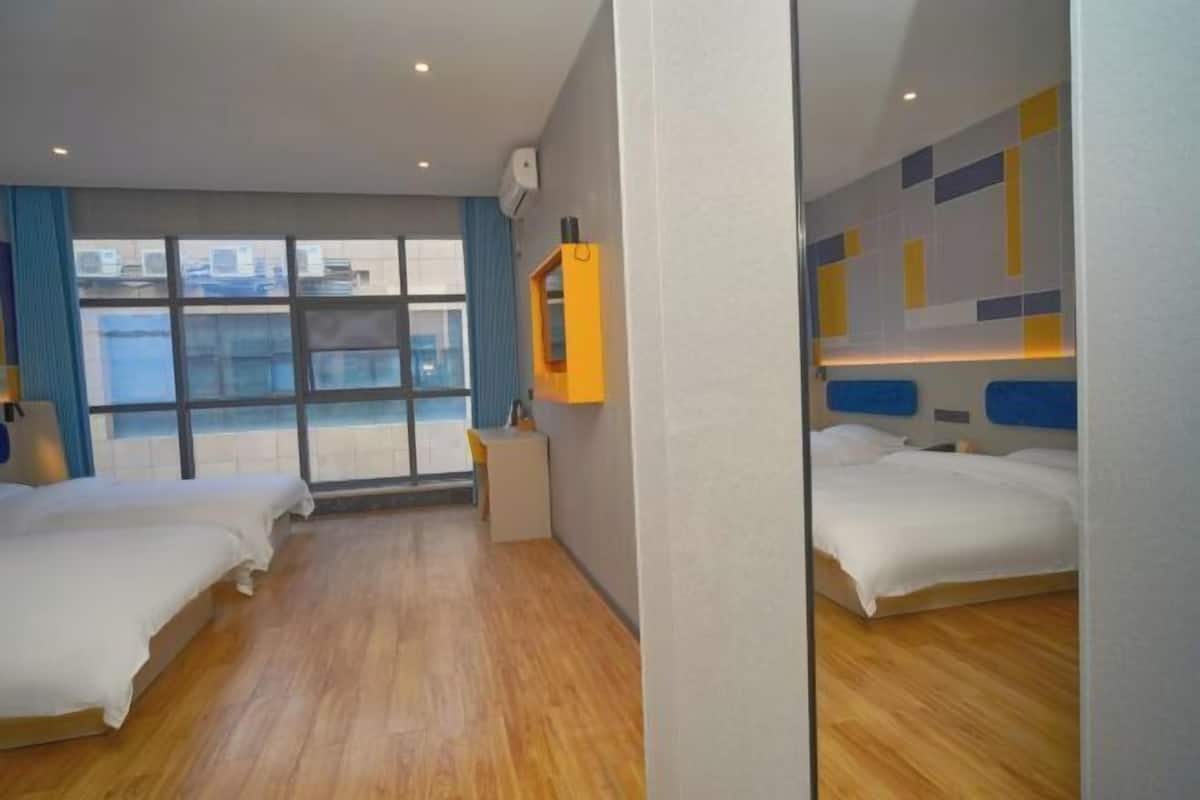 Une chambre d’hôtel avec deux lits, une fenêtre donnant sur un beau paysage, un petit bureau et un miroir.