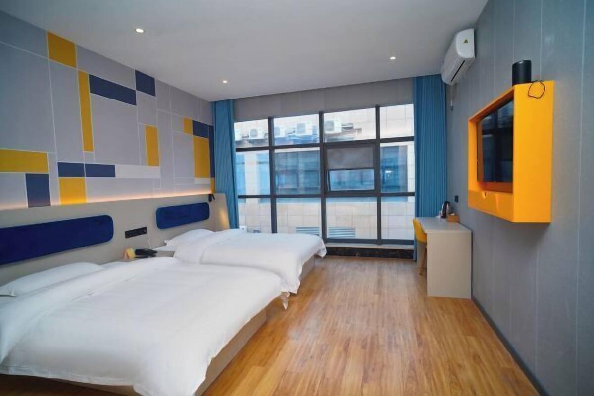Une chambre d’hôtel avec deux lits, un petit bureau, une fenêtre donnant sur un paysage agréable et un téléviseur fixé au mur.