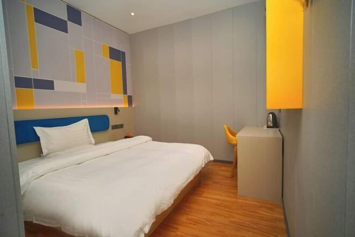 Une chambre d’hôtel avec un lit, un petit bureau et une chaise.