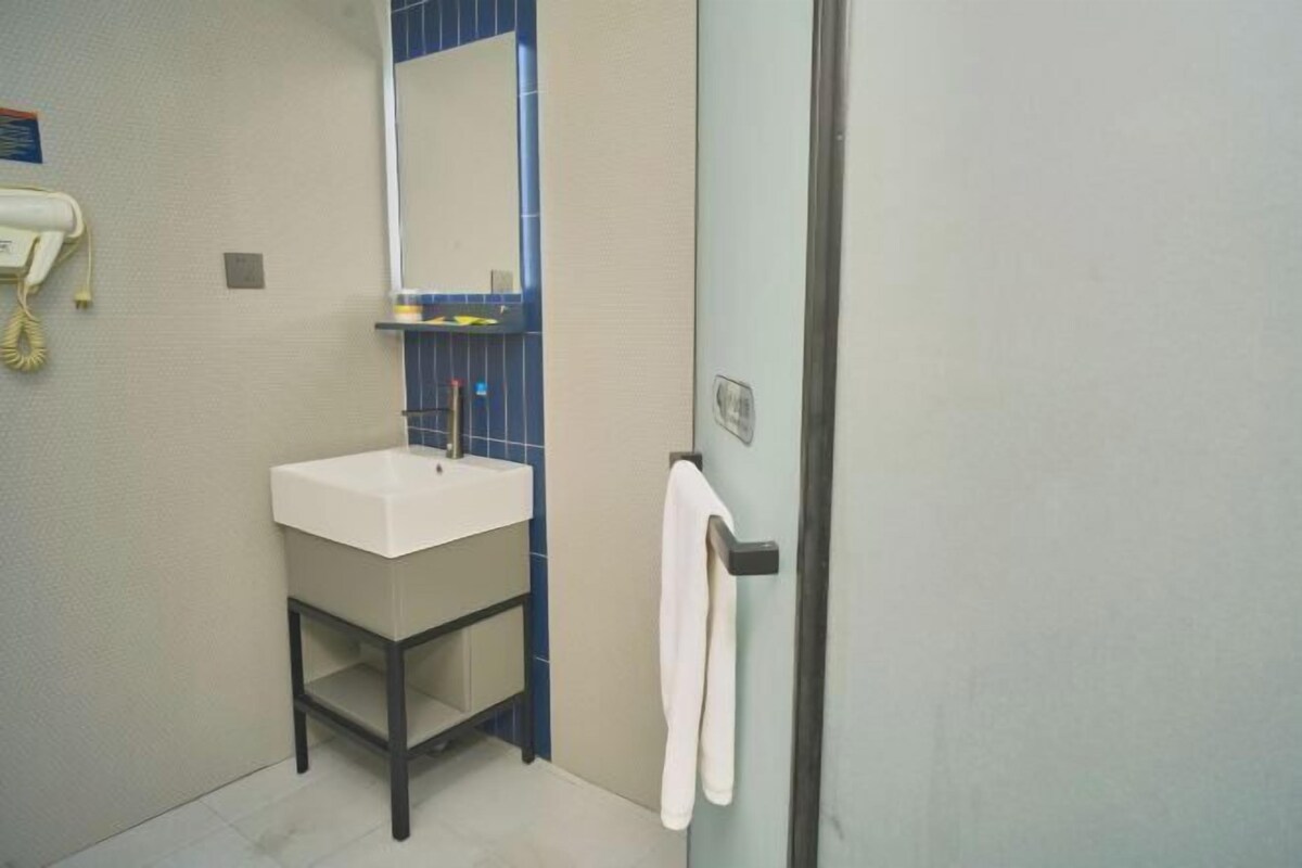 A bathroom with a white sink, blue-tiled wall, and a towel hanging on a door handle.