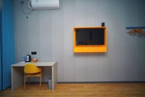 A room with a wooden floor, a desk with a chair, a mounted television, and a wall-mounted air conditioner. - 7Days Inn Chain Hotel (Chongqing Bund International) (Chongqing)