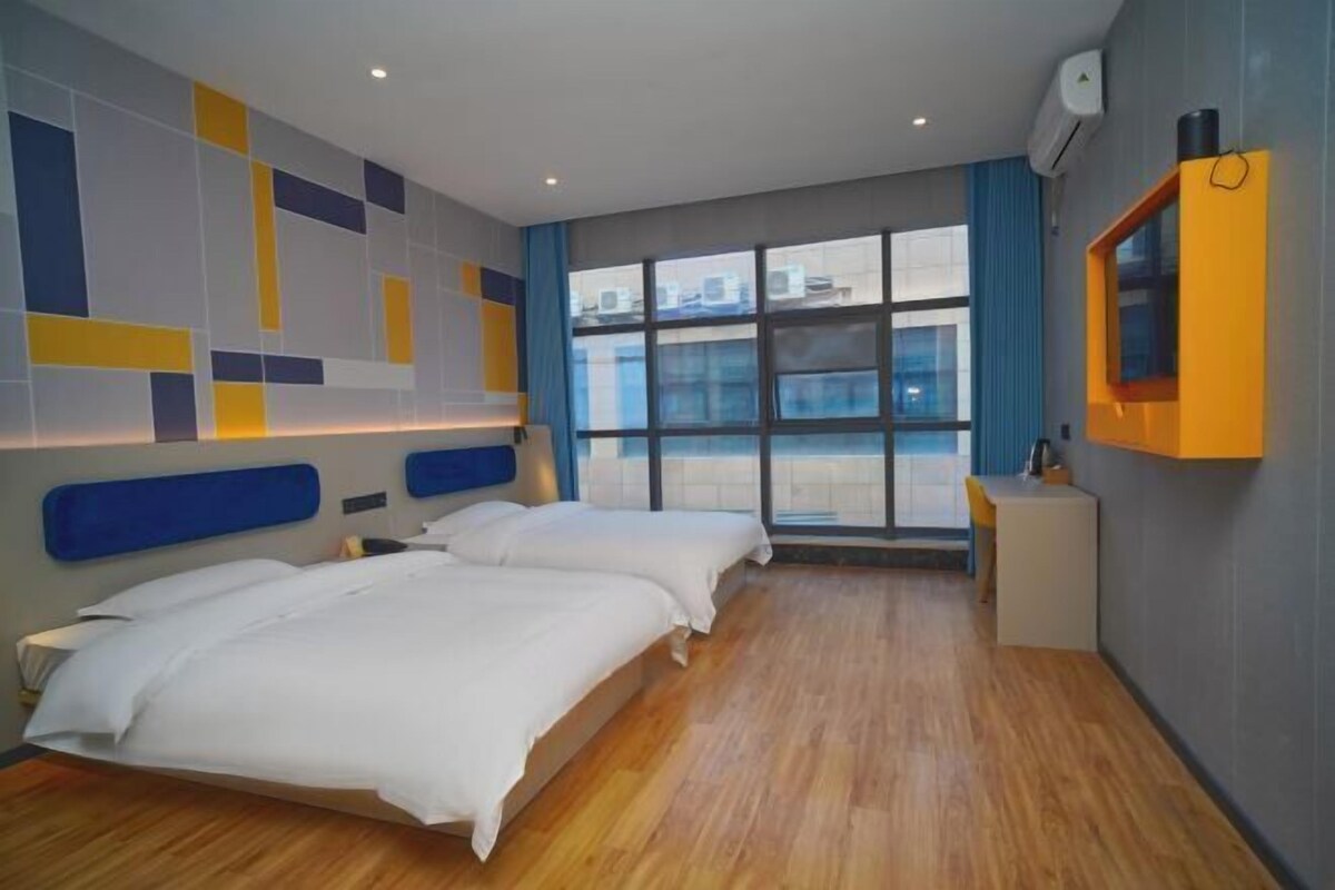 A hotel room with two beds, a large window, and a modern design with geometric wall patterns.