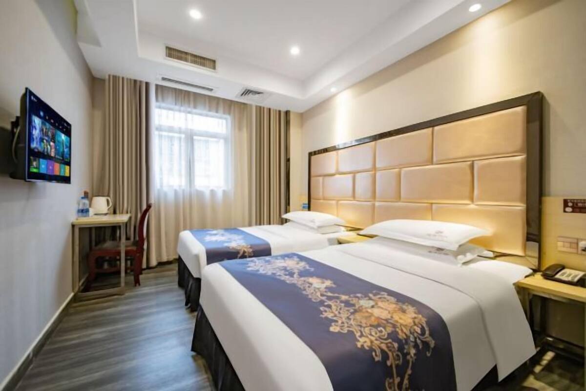 A hotel room with two beds, a TV, a desk, and a chair.