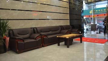 Un hall con un sofá, una mesa de centro y una recepción.
