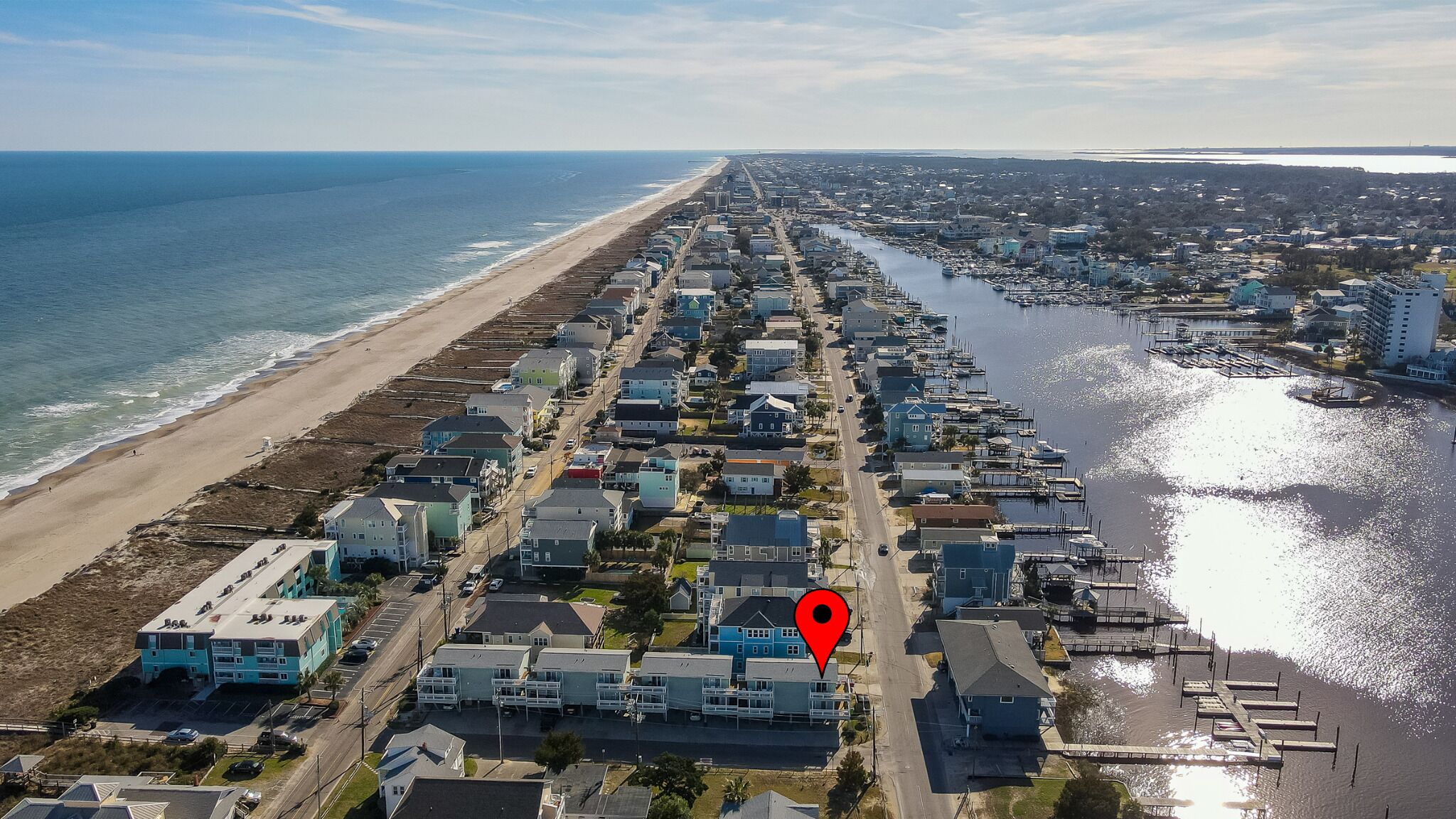 Luchtbeeld van een kustgebied met woonhuizen, een strand en een jachthaven.