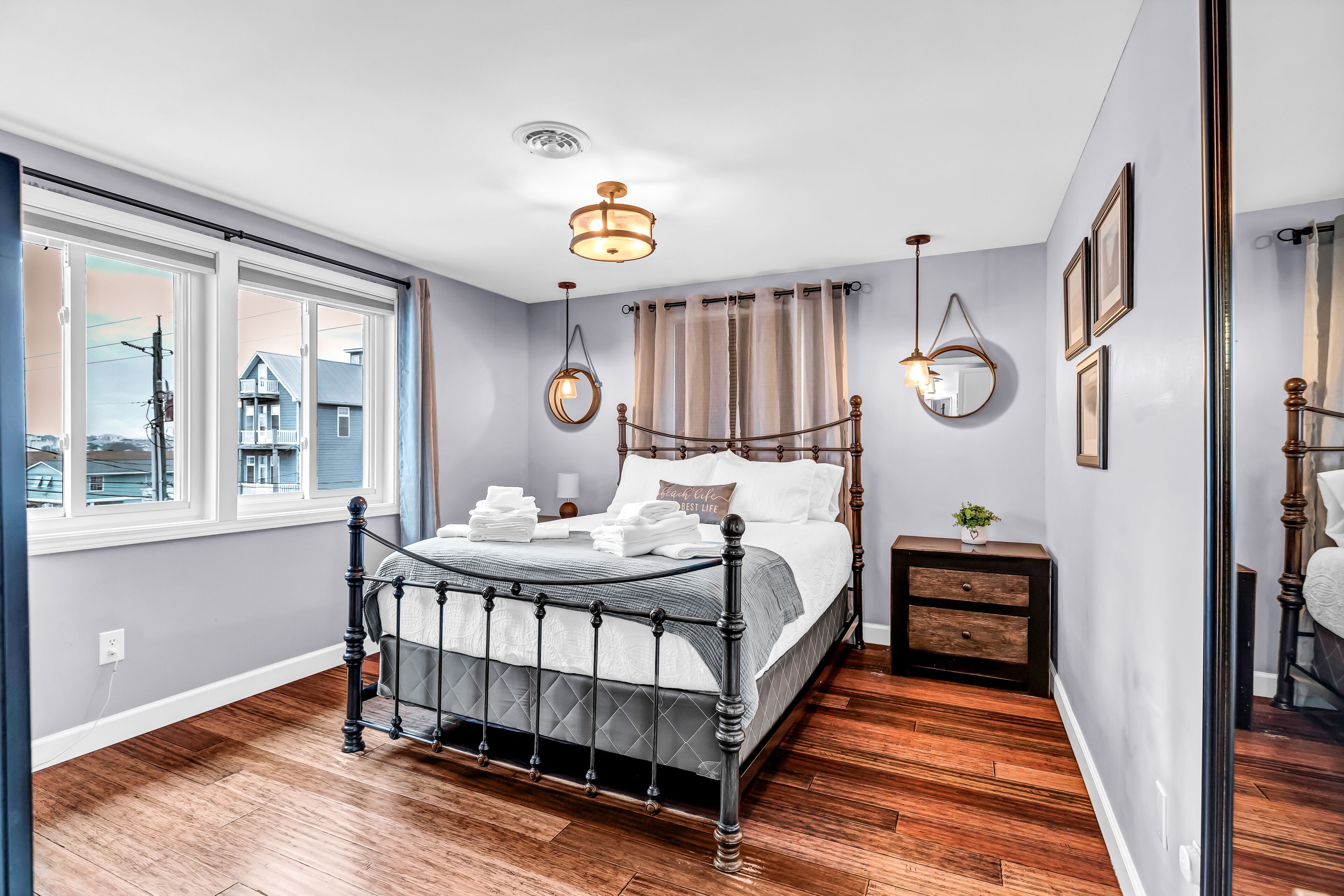 Un dormitorio con una cama grande, una mesita de noche, un espejo y una ventana con cortinas.