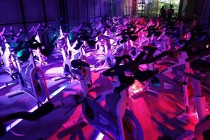 Varias bicicletas estáticas en un gimnasio con una hilera de espejos.