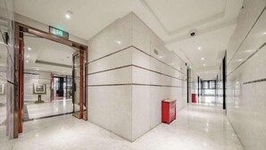 Un moderno vestíbulo de hotel con piso de mármol, una recepción y puerta de vidrio de entrada.
