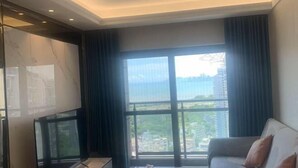 Una sala de estar moderna con un amplio ventanal, un televisor de pantalla plana y un sofá.