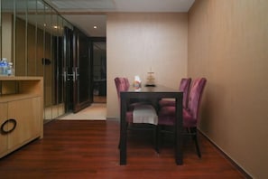 Un comedor con mesa y sillas de madera, una partición de vidrio y un armario de madera.