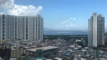 Un edificio residencial alto con varios pisos, rodeado de otros edificios y un cuerpo de agua al fondo.
