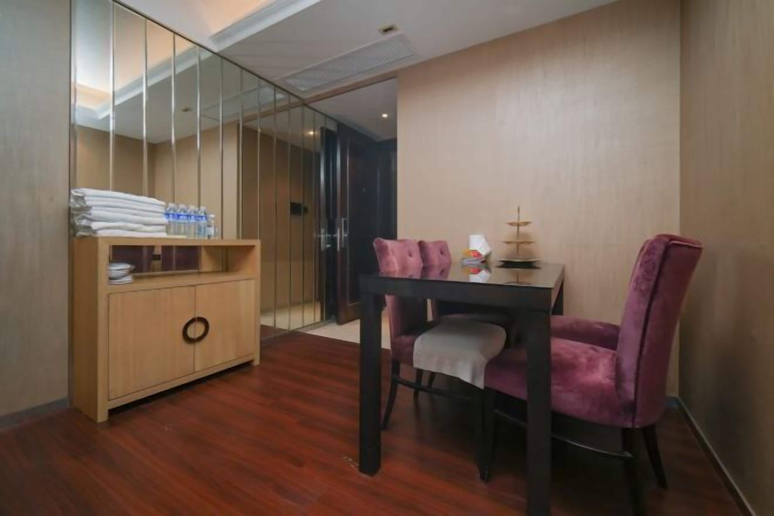 A modern room with a wooden cabinet, a dining table with two purple chairs, and a glass partition.