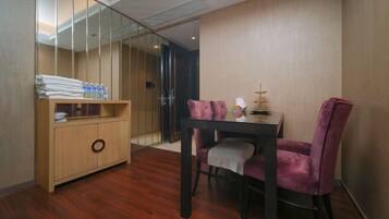 A modern room with a wooden cabinet, a dining table with two purple chairs, and a glass partition.