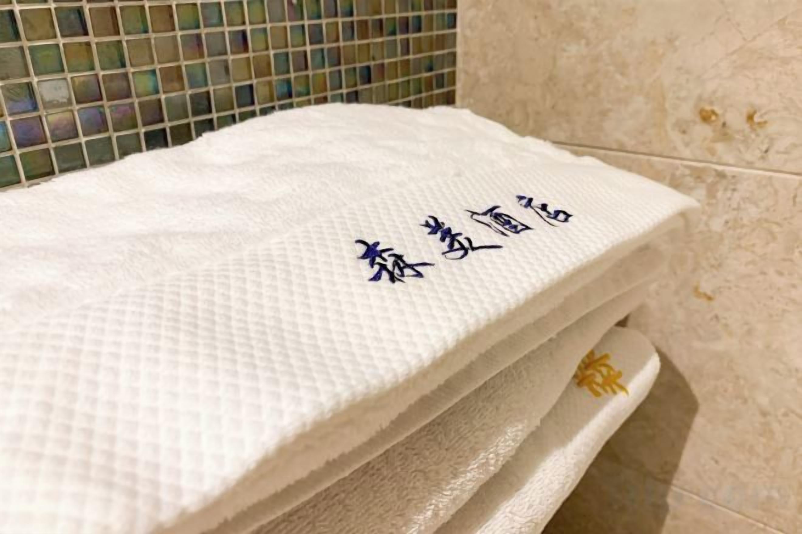 A white towel with embroidered characters on a bathroom counter.