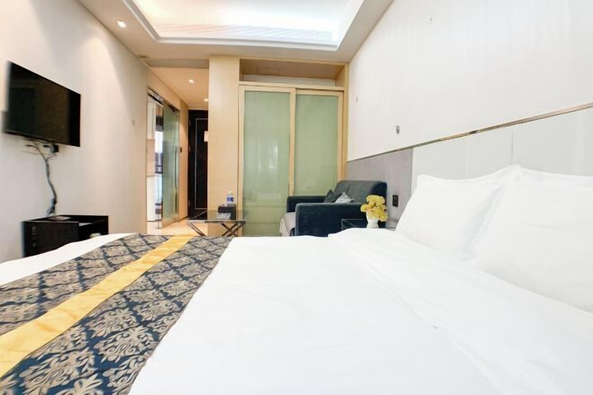 A hotel room with a bed, a TV mounted on the wall, a desk, and a chair.