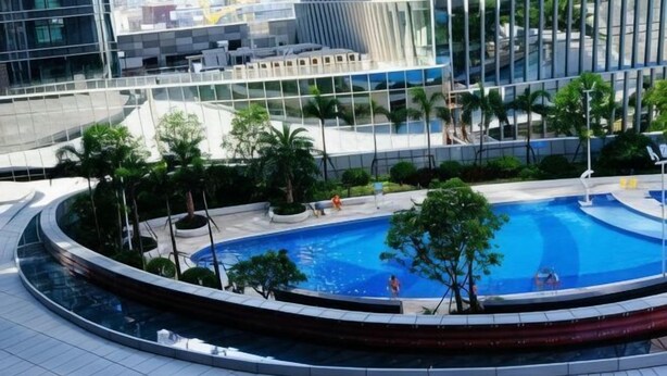 Una piscina en la azotea rodeada de vegetación y edificios modernos.