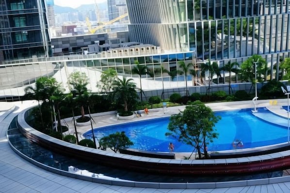 Une piscine sur le toit, entourée de verdure et de bâtiments modernes.