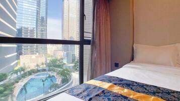 A hotel room with a large window offering a view of high-rise buildings and a pool.