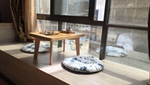 Een gezellige zithoek met een houten tafel en twee gekleurde kussens op een vensterbank.