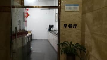 A corridor leading to a reception area with a sign indicating a breakfast area.