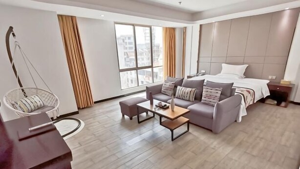 Een moderne hotelkamer met een bank, een bed, een hangstoel en een houten bijzettafeltje.
