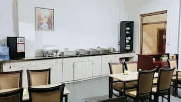 A dining area with tables and chairs, a refrigerator, a coffee machine, and a microwave.
