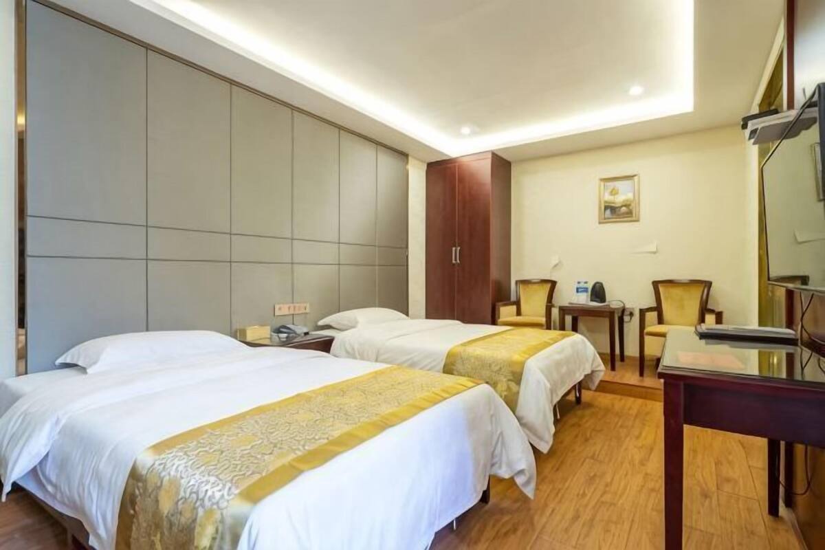 Quarto de hotel com duas camas, uma escrivaninha, uma cadeira e um espelho grande.