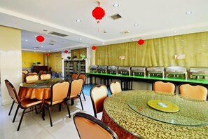 A dining area with a round glass table surrounded by chairs, a buffet counter with food display cases, and red lanterns hanging from the ceiling.