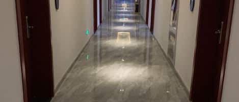 A long, narrow hotel corridor with doors on both sides, leading to rooms.