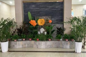 Zona de recepción con un banco de piedra, plantas en macetas y un cuadro abstracto grande en la pared.