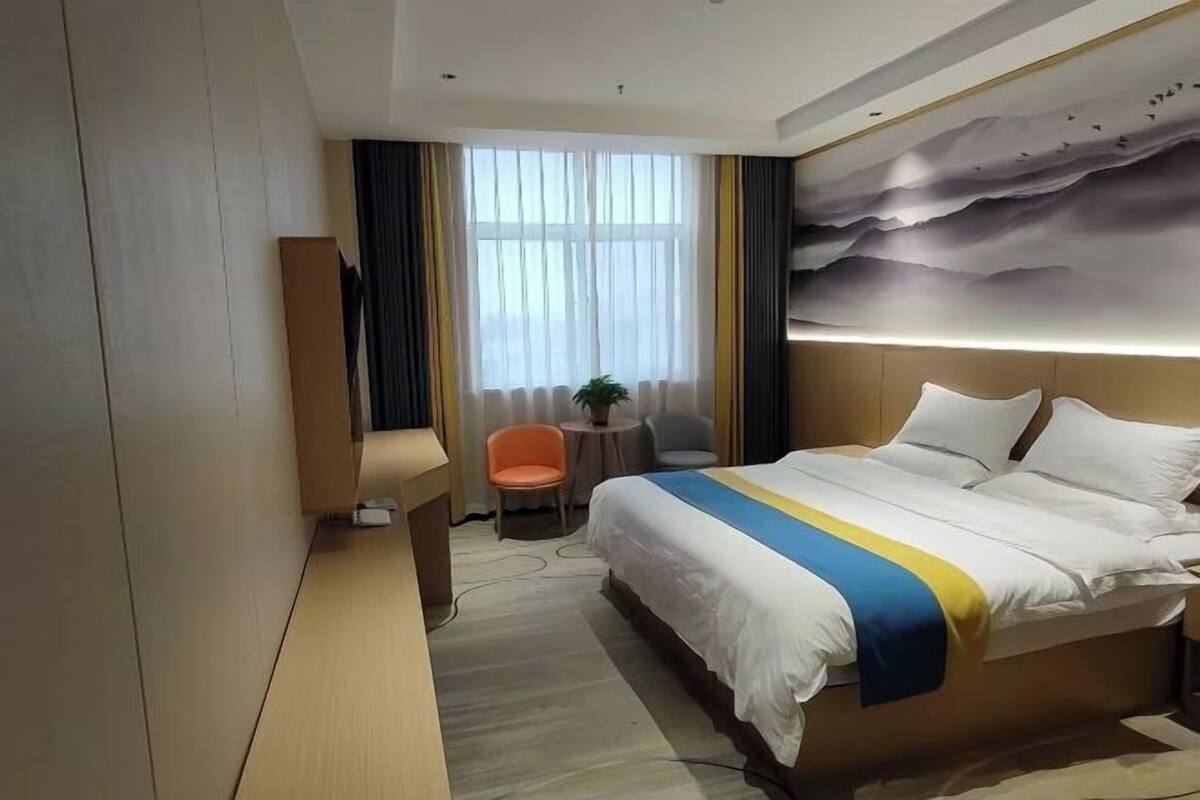 Habitación de hotel con una cama grande, un escritorio, una silla y vistas al exterior a través de una ventana.
