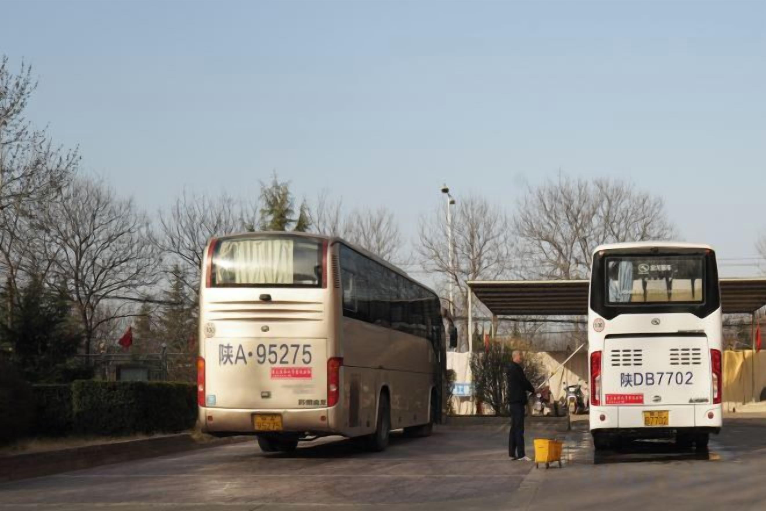 Zwei Busse an einem Busbahnhof, strahlend blauer Himmel.