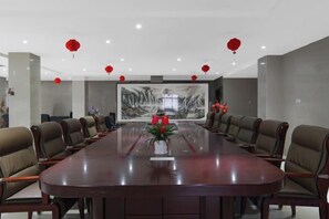 Un salón de conferencias con una larga mesa, sillas, una pantalla grande y faroles rojos.
