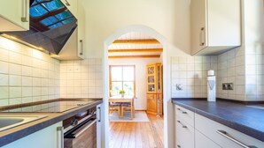 Een moderne keuken met een centraal eiland, houten vloeren en uitzicht op de eetruimte.